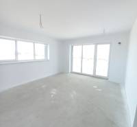 Tágas szoba egy kétszobás lakásban világos falakkal és nagy ablakokkal.