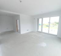 Világos nappali egy kétszobás lakásban nagy ablakokkal és üres padlóval.