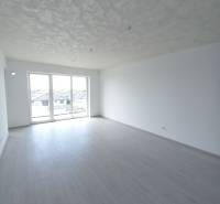 Világos szoba fa dekor padlóval és nagy ablakokkal egy kétszobás lakásban.