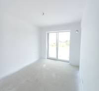 Világos szoba egy kétszobás lakásban nagy ablakkal és fehér falakkal.