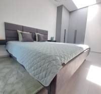 Hálószoba egy kétszobás lakásban felső ablakból érkező fénnyel és minimalista berendezéssel.