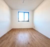 Kilátás egy fehér falú és fa dekor padlójú szobára egy családi házban.