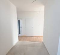 Folyosó egy családi házban, két fehér ajtóval és fa mintázatú padlóval.