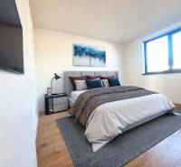 Hálószoba családi házban ággyal, képpel, TV-vel és fa dekorációjú padlóval.