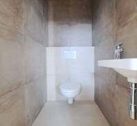 WC egy családi házban bézs kerámia burkolattal és mosdóval.