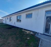 Családi ház Galántán fehér homlokzattal, nagy ablakokkal, építés alatt álló környezettel.