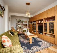 Nappali egy háromszobás lakásban, szőnyeggel és fa dekorációjú padlóval.