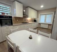 Konyha családi házban fehér bútorokkal és fa dekorációjú padlóval.