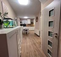 Családi ház belső tere konyhával, fehér bútorokkal és fa dekoros padlóval.