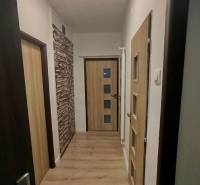 Folyosó világos padlóval és faajtókkal egy háromszobás lakásban.