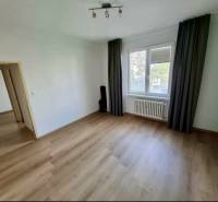 Szoba egy 4 szobás lakásban, fa dekorációjú padlóval, függönyökkel, radiátorral.