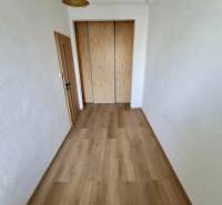 Folyosó egy 4 szobás lakásban fa mintázatú padlóval és beépített szekrénnyel.