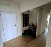 Folyosó egy 4 szobás lakásban fogassal, babakocsival és fa dekoros padlóval.