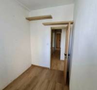 Szoba egy 4 szobás lakásban fa dekor padlóval és polcokkal a falon.