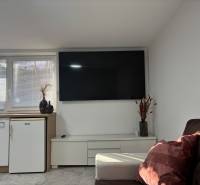 Nappali a családi házban televízióval és kanapéval, fa dekorációjú padlóval.