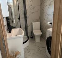 Fürdőszoba családi házban márványburkolattal, zuhanyzóval és mosógéppel.