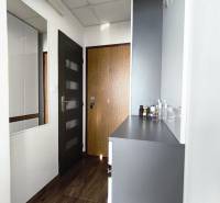 Folyosó fa mintázatú padlóval és fehér bútorokkal egy egyszobás lakásban.