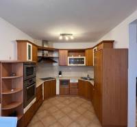 Konyha sarokpulttal és fa mintázatú padlóval egy háromszobás lakásban.