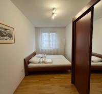 Hálószoba ággyal, beépített szekrénnyel és fa dekorációjú padlóval egy háromszobás lakásban.