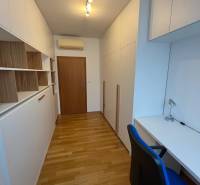 Dolgozószoba fehér bútorokkal, beépített szekrényekkel és fa dekor padlóval egy háromszobás lakásban.