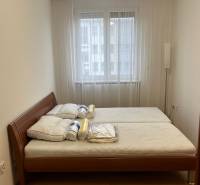 Hálószoba egy háromszobás lakásban ággyal és ablakkal, fa dekorációjú padlóval.