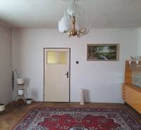 Nappali egy családi házban szőnyeggel, csillárral, képpel és vitrinnel.