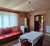 Családi ház belső tere kanapéval, étkezőasztallal és tűzhellyel.