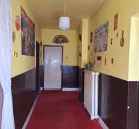 Folyosó sárga falakkal, piros szőnyeggel és függő lámpával egy családi házban.