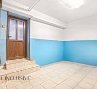 Családi ház belső tere kék falakkal és világos padlóval a faajtó mellett.