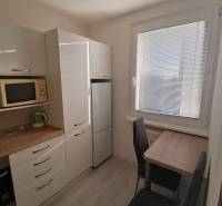 Konyha egy egyszobás lakásban, készülékekkel és redőnyös ablakkal.