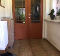 Családi házban: előszoba ajtókkal, fa dekoros padló, növények a párkányon.