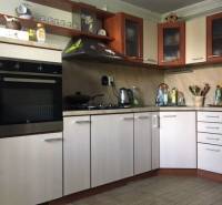 Konyha családi házban, fa dekoros padlóval és világos szekrényekkel.