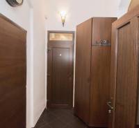 A sötét ajtókkal és tárolószekrényekkel rendelkező kétszobás lakás folyosója.