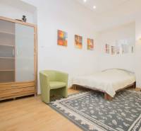 Hálószoba egy kétszobás lakásban, fa dekorációjú padlóval, szőnyeggel és ággyal.