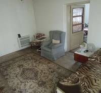 Szoba egy családi házban szőnyeggel, fotelekkel és ággyal.