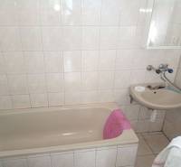 Fürdőszoba káddal és mosdóval családi házban, világos csempék és padlóburkolat.