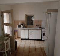 Konyha családi házban fehér szekrényekkel, mikrohullámú sütővel és hűtőszekrénnyel.