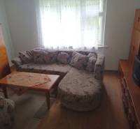 Nappali egy családi házban sarokkanapéval és asztallal, fa dekorációjú padlón.