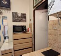 Garzonlakás konyhasarokkal, mikrohullámú sütővel, beépített szekrénnyel és tükörrel.