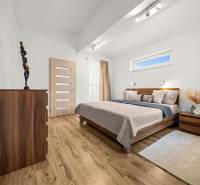 Hálószoba fa dekor padlóval, ággyal és komóddal egy családi házban.