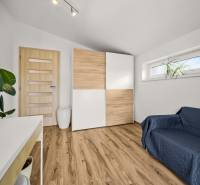 Szoba egy családi házban, fa dekoros padlóval, szekrénnyel és kanapéval.