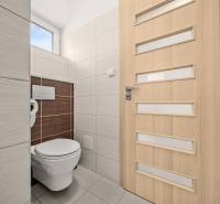 WC egy családi házban világos csempékkel és függőleges csíkos ajtókkal.