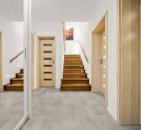 Családi ház előszobája fa mintázatú padlóval és lépcsővel.