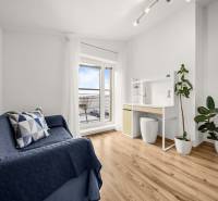 Szoba egy családi házban, fa mintázatú padlóval, kék kanapéval és íróasztallal.