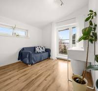 Szoba családi házban kanapéval, ablakokkal és fa dekorációjú padlóval.