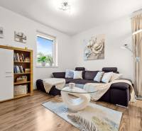 Nappali egy családi házban kanapéval, szekrénnyel, fa dekoros padlóval és dekorációkkal.