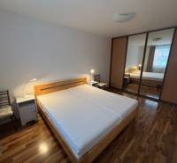 Hálószoba ággyal, tolóajtós szekrénnyel és fa dekoros padlóval.