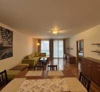 Nappali fa mintázatú padlóval, kanapéval és étkezőasztallal egy kétszobás lakásban.