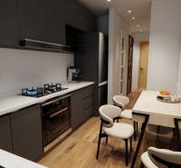 A háromszobás lakás konyhája tűzhellyel, étkezőasztallal és fa dekorációjú padlóval.