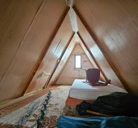 A kunyhó padlása matraccal és székkel, fa dekoráció, világos falak.